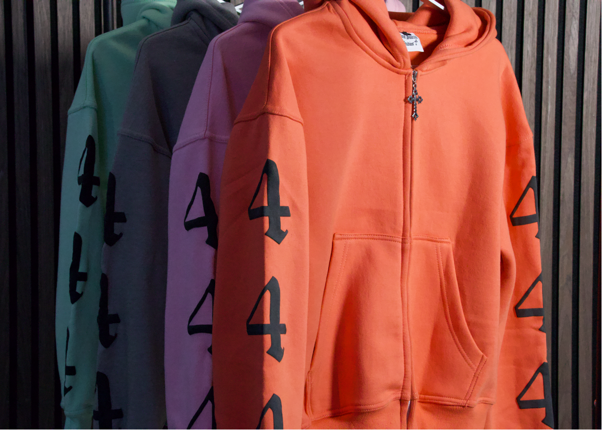 Four hoodies in different colors with a design on a striped background