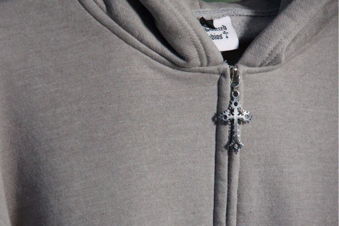 Gray hoodie with a zipper and decorative pendant on a dark background